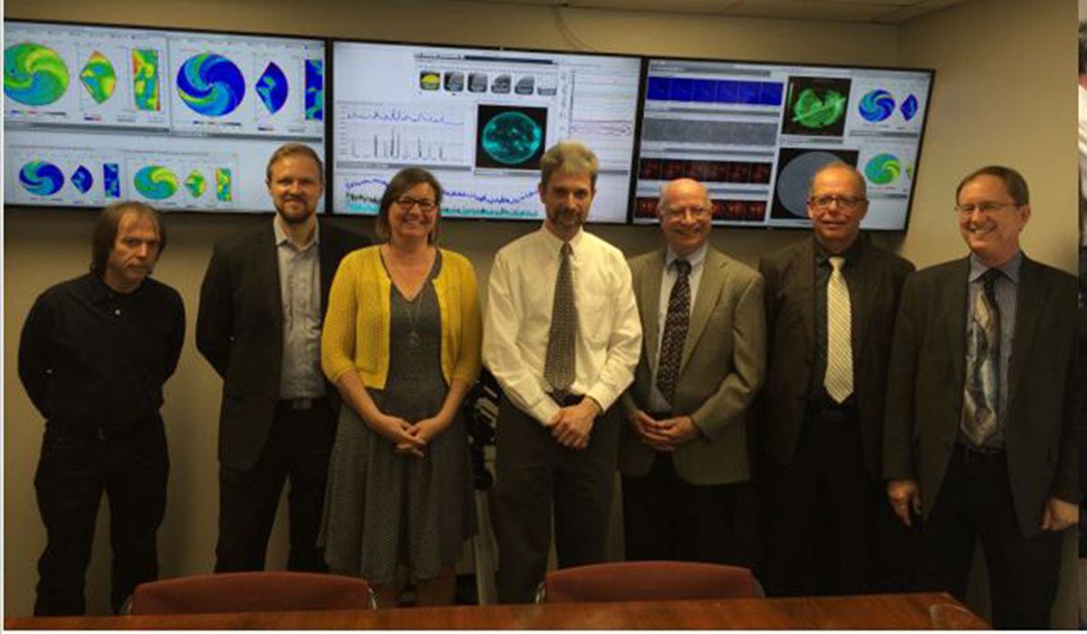 Space Weather lab staff standing in front of screens depicting space weather charts