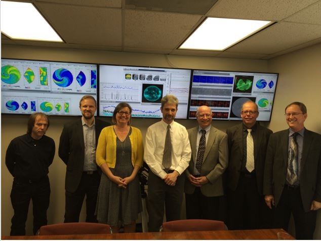 Space Weather staff standing in front of screens depicting space weather charts